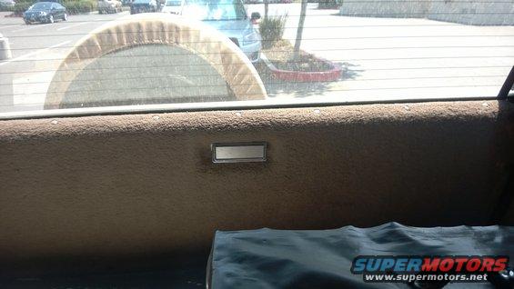 Interior rear panel with spare tire cover visible through window. Other vehicles seen outside