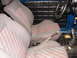 1964 Volkswagen Beetle - The interior of the vehicle shows patterned seats and a dashboard with a steering wheel and gear shifter.