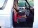 1990 Ford Bronco - The interior of a truck features custom seats with red and black flame upholstery and a prominent center console with cup holders.