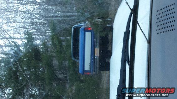Blue SUV with a white stripe on the tailgate, seen from the rear