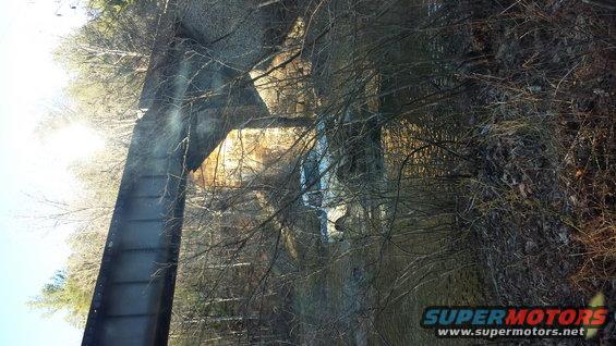 Ford Bronco parked near a bridge in a wooded area