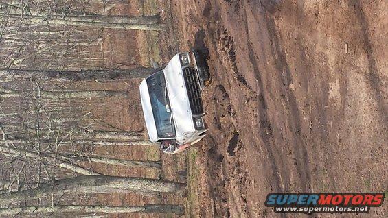 White SUV on muddy trail, front grille visible
