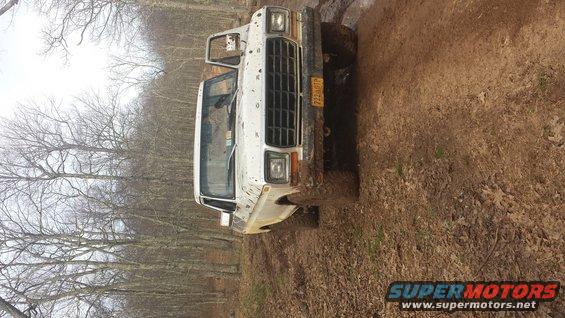 1979 Ford Bronco on a muddy trail, front end visible, driver's door open