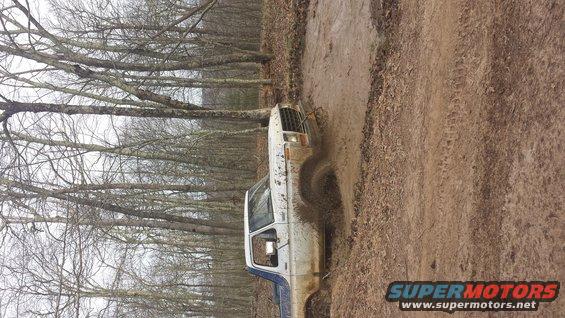 1979 Ford Bronco stuck in mud, front quarter view, white with blue trim, mud splattered