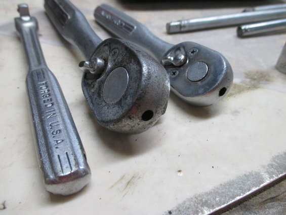 Three metal ratchet wrenches, one with "FORGED IN U.S.A." visible, on a light-colored surface