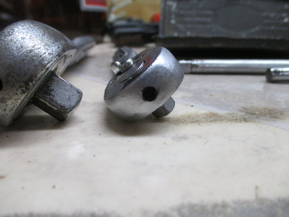 Two metal ratchet heads on a tiled surface