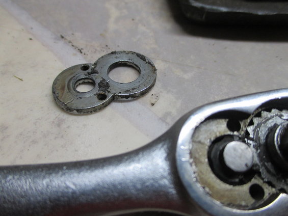 Close-up of a metal part with two circular openings and a ratchet wrench mechanism