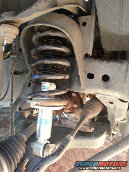 Front strut assembly with Bilstein shock absorber and coil spring. Visible CV axle and suspension components