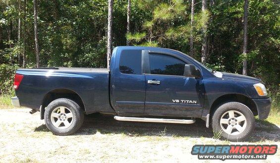 Blue pickup truck with V8 TITAN badging, side view, parked outdoors