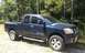 2006 Nissan Titan - Dark blue 2006 Nissan Titan pickup truck parked on a dirt surface with trees behind it.