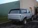 1990 Ford Bronco - Rear view of a silver 1990 Ford Bronco with a black top, parked outdoors.