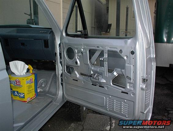 Silver vehicle interior, driver's door open, showing door panel removed. Box of rags on floor