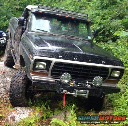 Black Ford Bronco with off-road tires and winch, angled from the front right, on a rocky trail