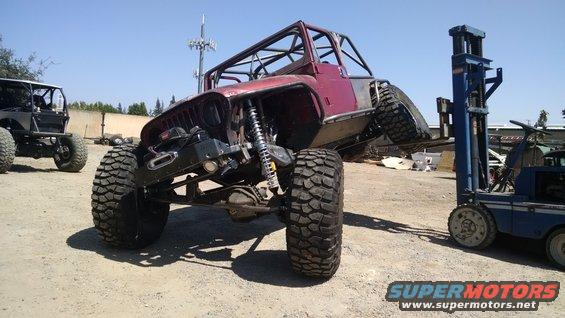 Custom off-road Jeep with roll cage and large tires, being lifted by a forklift