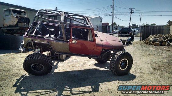 Custom Jeep CJ with roll cage and large tires, parked outside