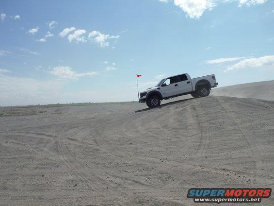 White pickup truck on sand dune, 2010 model year