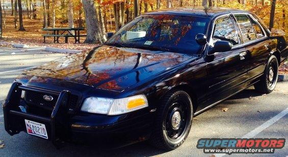 Black 2006 Ford Crown Victoria with a push bar, parked outdoors in autumn