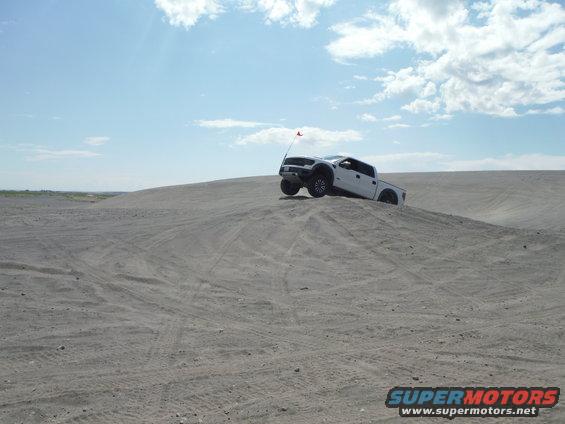 White pickup truck with a red flag on a sand dune
