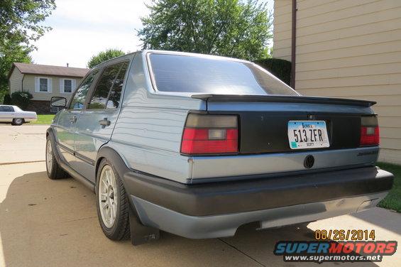 Rear view of a light blue 1990 Volkswagen Jetta with a black panel on the trunk