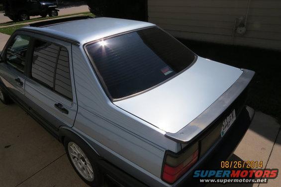 Silver sedan with a spoiler and tinted windows. A black Jeep is parked in the background