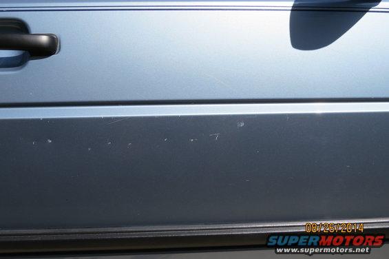 Blue car door panel with black handle and minor scratches