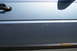 1990 Volkswagen Jetta - Close-up of a blue car door panel showing a black door handle and some scuffs.