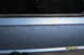 1990 Volkswagen Jetta - A close-up view of a blue car's side panel shows minor imperfections and a reflection in the window.