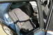 1990 Volkswagen Jetta - The interior rear seats of a blue car are visible, with fabric upholstery and the open door frame.
