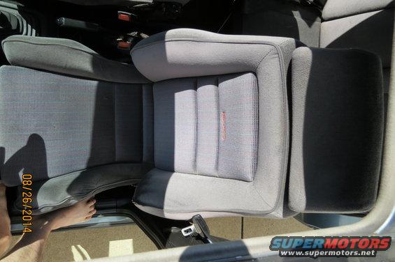 Gray fabric car seats with a red logo on the passenger seat. A foot is visible near the door