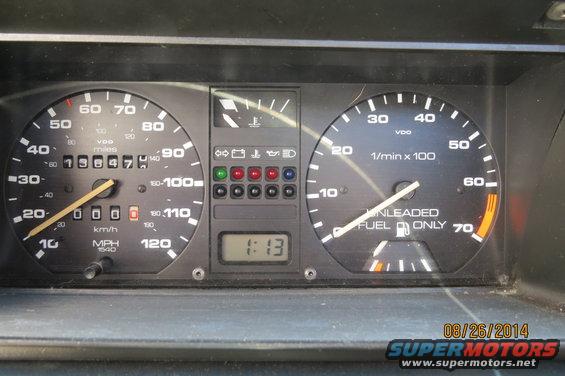 Close-up of car dashboard gauges showing speedometer, tachometer, fuel level, and digital clock