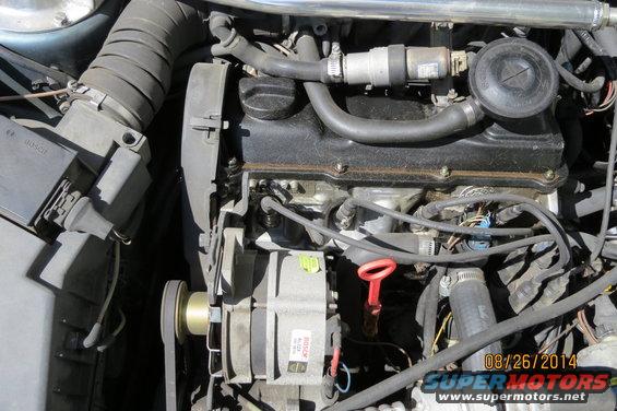 Close-up of a Volkswagen engine bay, showing the alternator, air intake, and engine cover