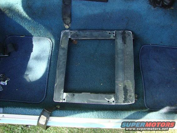 Seat mounting bracket on blue carpeted floor with seatbelt visible