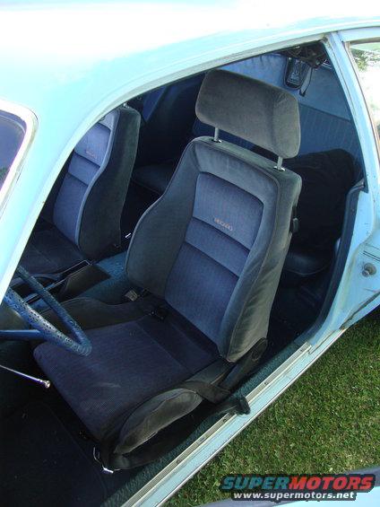 Car interior showing front bucket seats with Recaro branding, blue upholstery, and a steering wheel