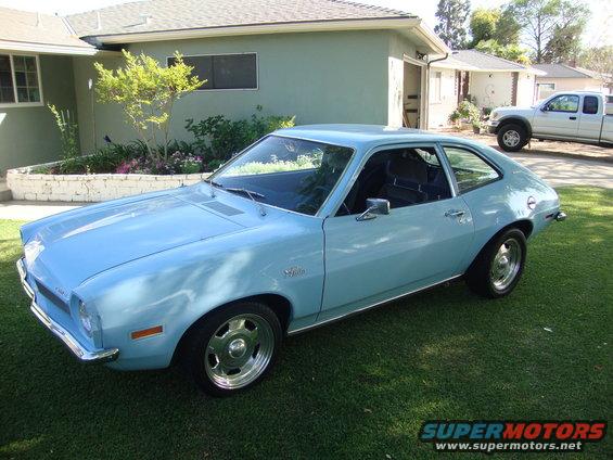 Light blue 1972 Ford Pinto coupe parked on a lawn in front of a house