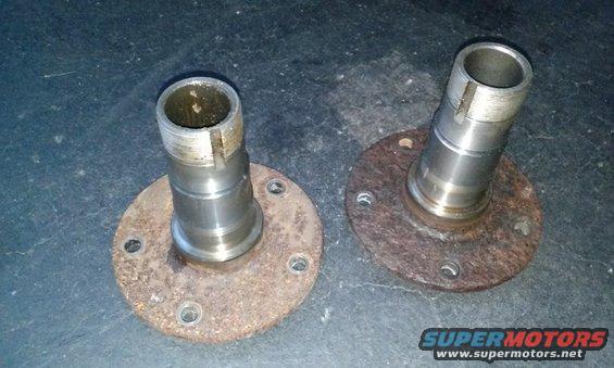 Two rusty wheel hubs with bolt holes and splined shafts