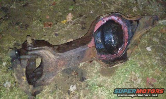 Differential axle assembly with red gasket sealant, resting on grass