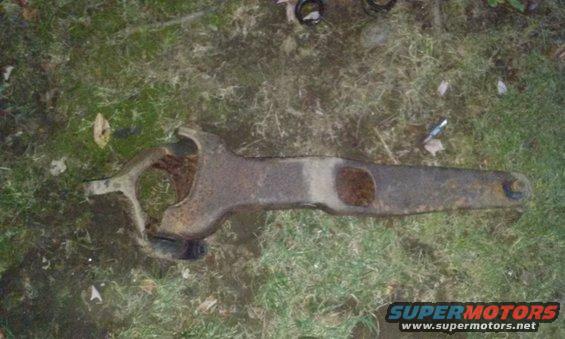 Rusted metal suspension part on grass, Supermotors.net logo visible