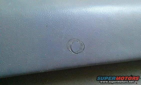 Gray textured interior trim panel with a circular mark, possibly from a removed emblem or button