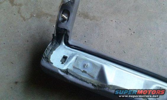 Close-up of a damaged chrome car bumper corner with visible adhesive and mounting points