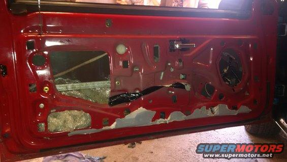 Disassembled red car door interior showing internal mechanisms and sound deadening material