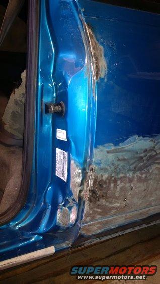 Blue car door interior with visible rust and repair work on the lower edge