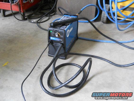 Miller welding machine with cables and hoses on concrete floor