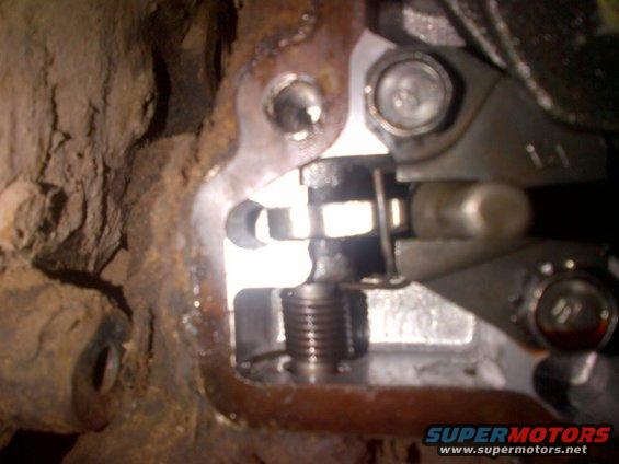 Close-up of a rusty metal bracket with a spring-loaded mechanism and a bolt