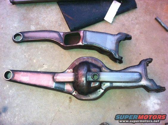 Two metal automotive differential housings and axle components laid on a concrete floor