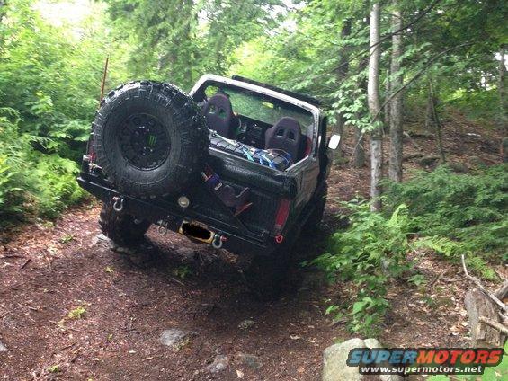 Black SUV with spare tire on rear, off-roading in woods