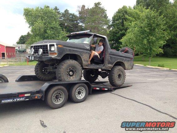 Black 1979 Ford Bronco on trailer, 3q-front view. Lifted with large tires