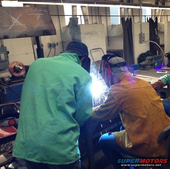 Two people welding in a workshop, sparks flying