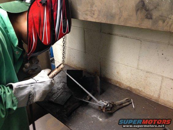 Person welding metal parts on a workbench