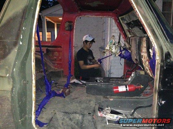 Interior of a disassembled vehicle with a person working inside and a fire extinguisher visible