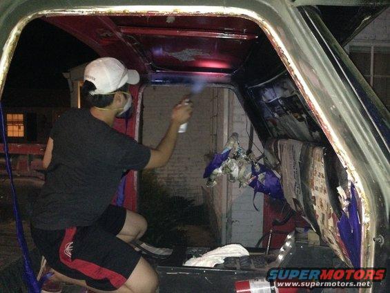 Person spraying inside a vehicle's interior, showing red and black panels